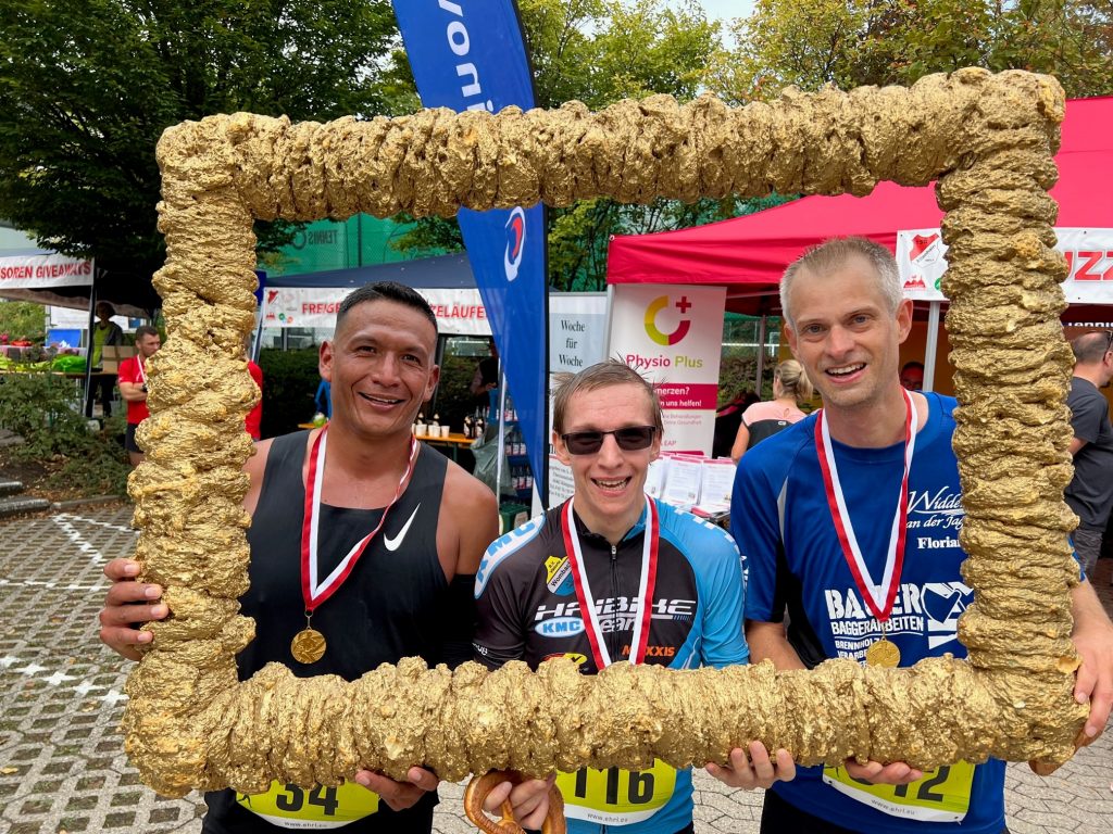 Siegerrehrung der Männer. Im goldenen Rahmen drei Männer.